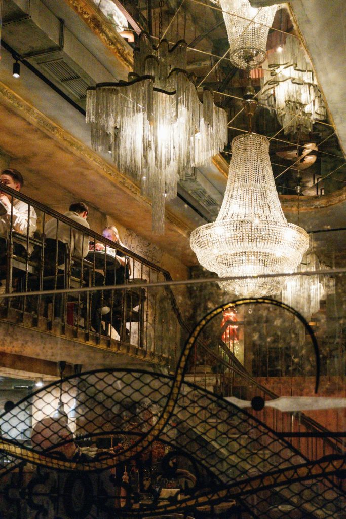 Elegant chandeliers illuminate a dimly lit, ornate interior.